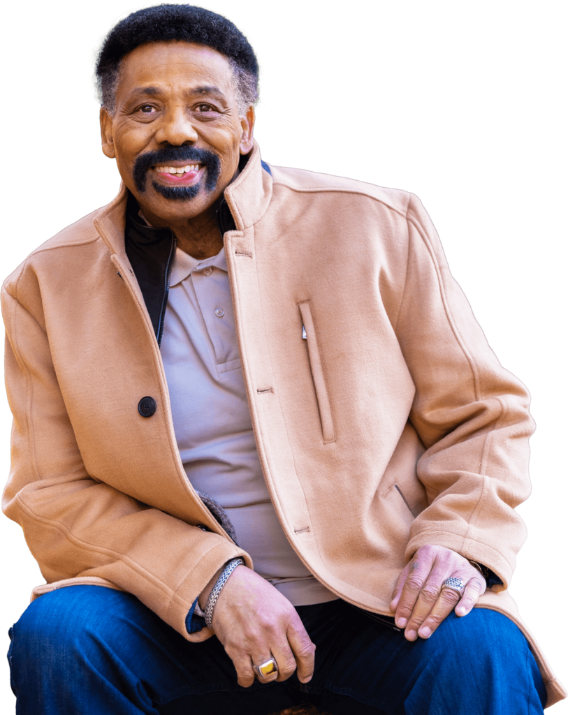 Tony Evans in a light brown coat sitting on a rock and smiling